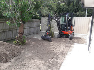Mini digger levelling soil in preparation for a lawn